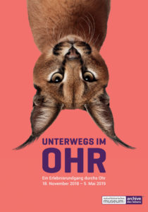 Das Plakat der Ausstellung "Unterwegs im Ohr" zeigt einen Luchs, der auf dem Kopf steht. 