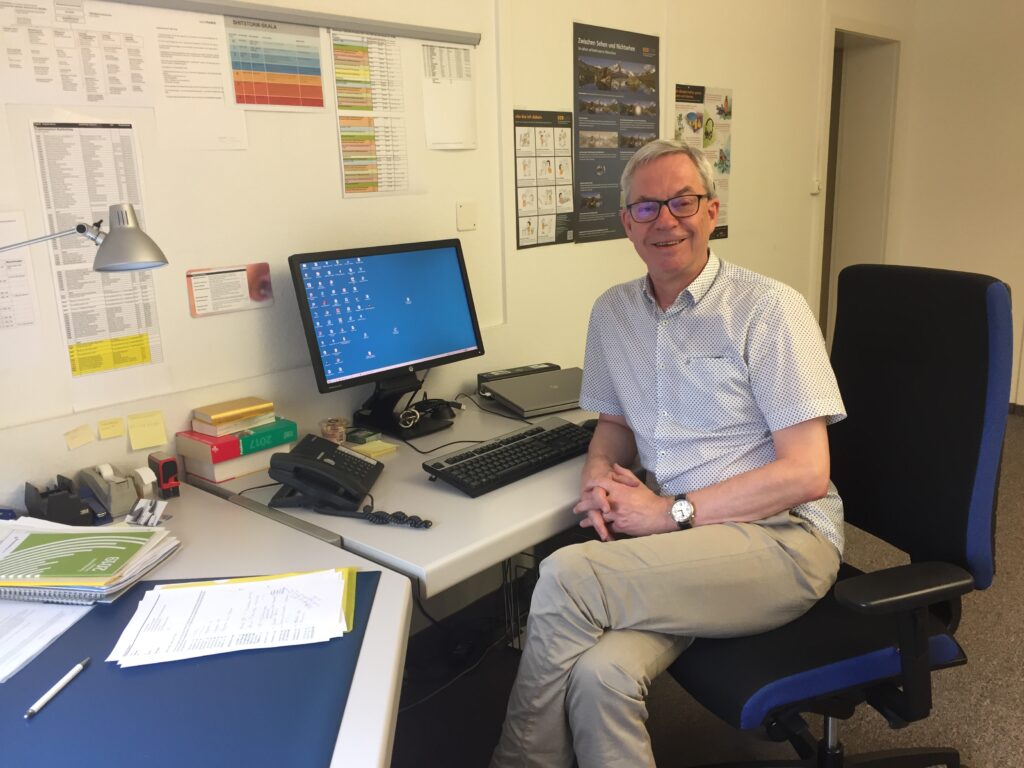 Norbert Schmuck sitzt an seinem Arbeitstisch in seinem Büro.