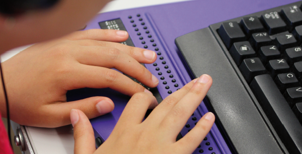 Das Bild zeigt die Hände einer Person auf einer Braillezeile. 