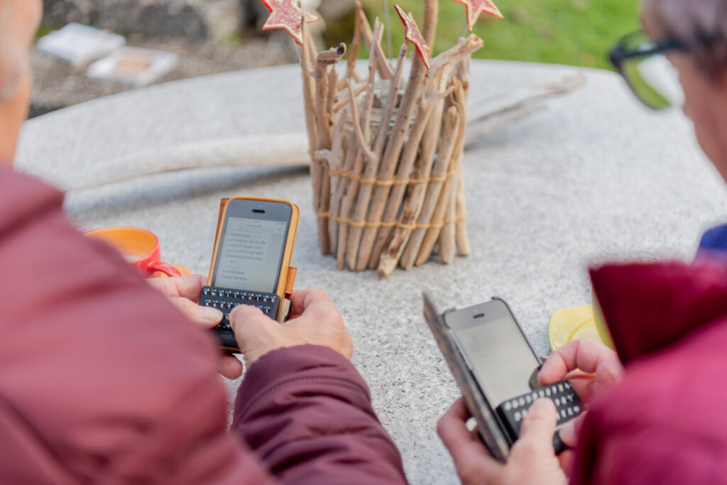 das Bild zeigt zwei Menschen, die mit der Tastatur help2type SMS schreiben. 