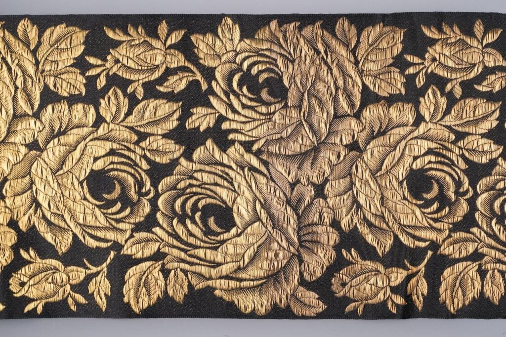 Des roses avec des feuilles et des boutons de rose sont brodées sur le ruban de soie noir. 